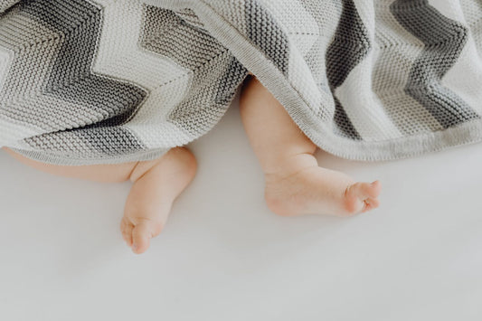 pied de bébé sortant d'une couverture rayée grise, cadeau de naissance made in france