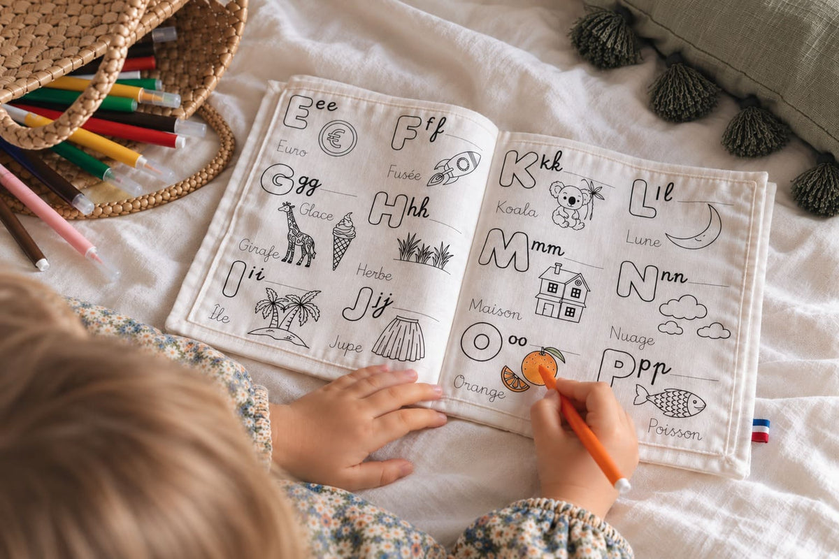 enfant de 3 ans qui colorie une page du cahier d'activités maternelle avec des lettres