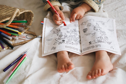 enfant de 3 ans qui colorie un cahier de coloriage lavable mappemonde posé sur ses genoux