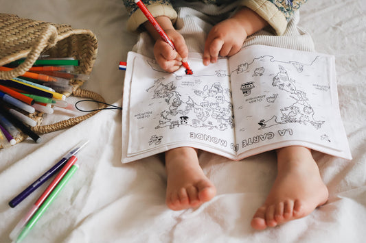 enfant de 3 ans qui colorie un cahier de coloriage lavable mappemonde posé sur ses genoux