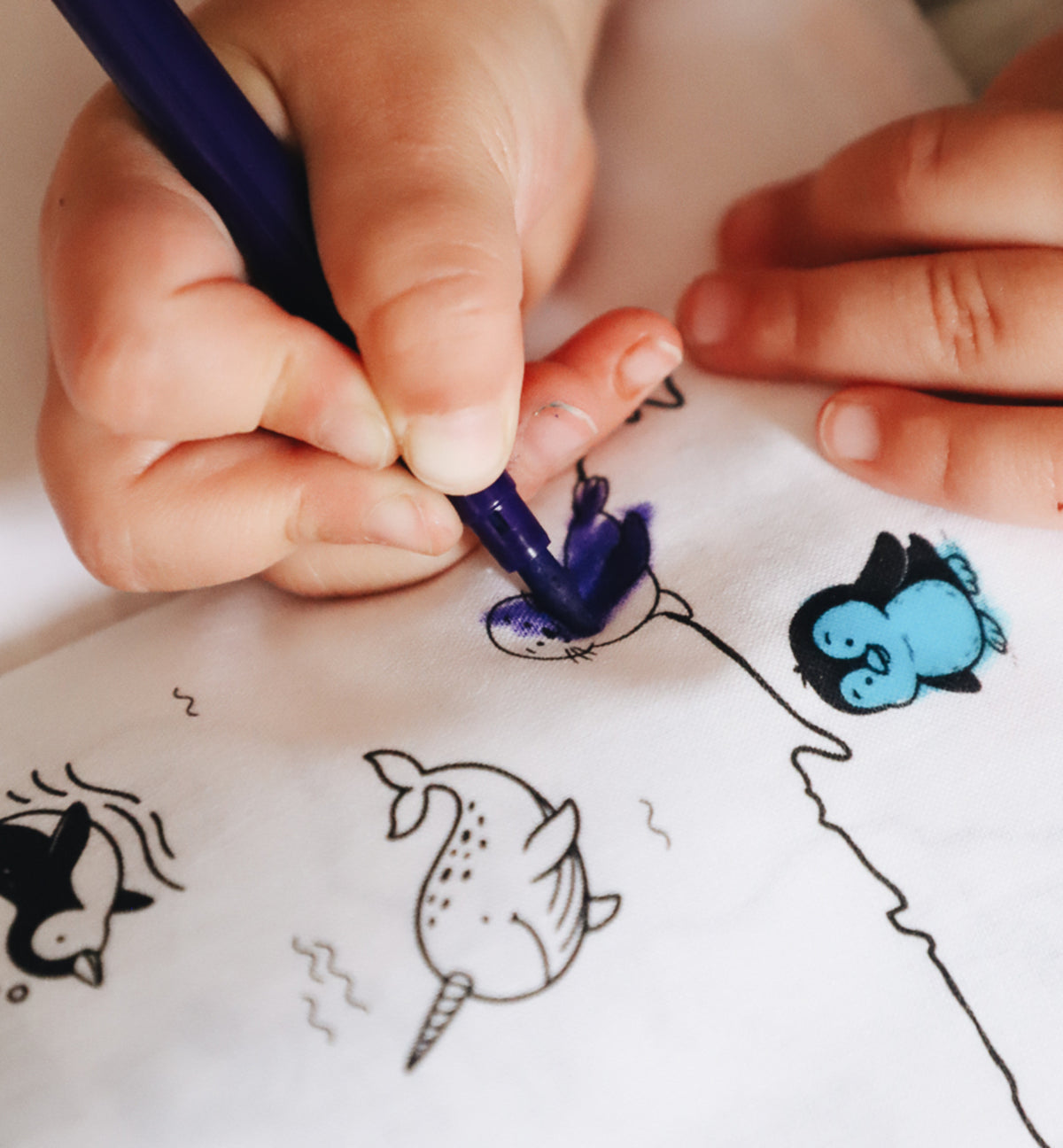 zoom d'un enfant qui colorie des animaux du cahier de coloriage lavable mappemonde fabriqué en France