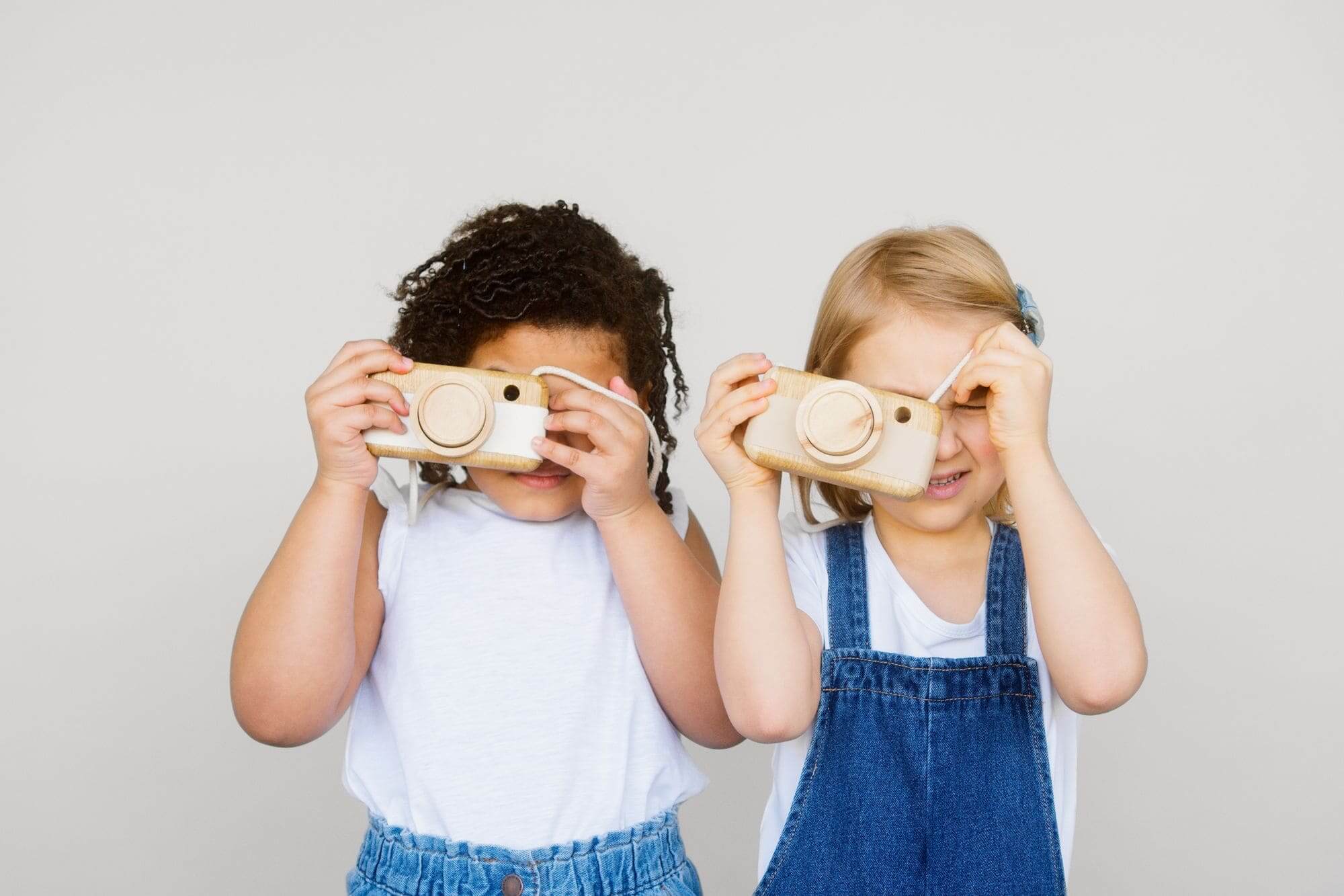 2 petites filles de 6 ans faisant semblant de prendre une photo avec leur jouet appareil photo en bois made in france