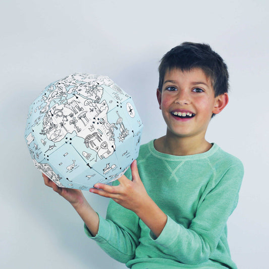 garçon de 7 ans souriant et tenant dans ses mains la terre 3D qu'il a fabriqué