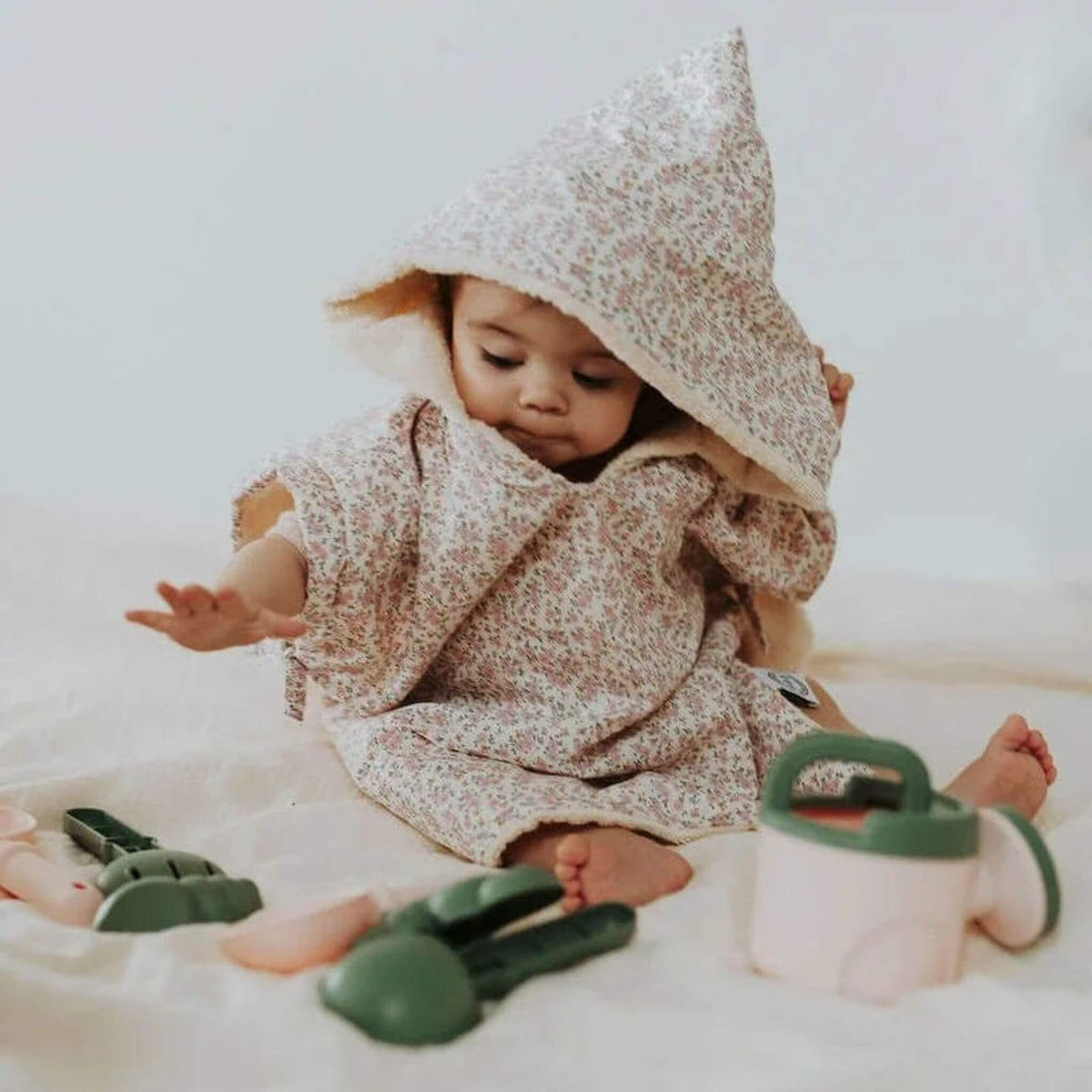 enfant de 2 ans vêtue d'un poncho de bain et jouant sur un tapis